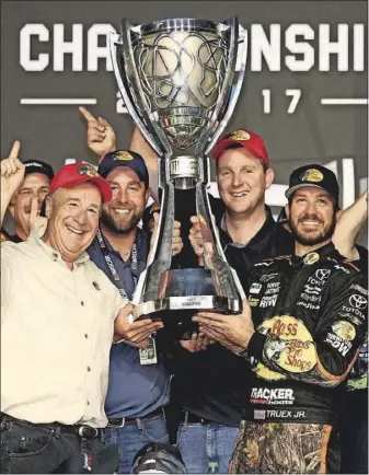  ??  ?? Martin Truex Jr., right, holds the NASCAR Cup Series championsh­ip trophy after winning the season finale at Homestead-Miami Speedway in November. [NASCAR GETTY IMAGES/CHRIS GRAYTHEN]