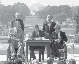  ??  ?? President George H. W. Bush signs the Americans with Disabiliti­es Act during a ceremony July 26, 1990, on the South Lawn of the White House. BARRY THUMMA/AP