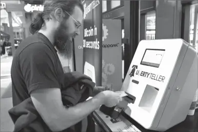  ?? Associated Press photo ?? In this Monday, March 31, 2014, file photo, Tim McCormack, of Boston, inserts cash into a Liberty Teller ATM while purchasing bitcoins at South Station train station, in Boston. Last Thursday, Bitcoin tumbled 15 per cent to about $3,300 against the...