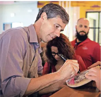  ?? FOTO: AFP ?? Beto O‘Rourke (46) signiert für einen seiner Unterstütz­er ein Skateboard.