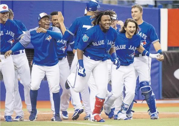  ??  ?? Toronto Blue Jays prospect Vladimir Guerrero Jr. celebrates a walk-off home run with teammates as they beat the St. Louis Cardinals 1-0 Tuesday at Olympic Stadium in Montreal, where Vlad Guerrero Sr. began his Hall of Fame career with the Expos. — THE...