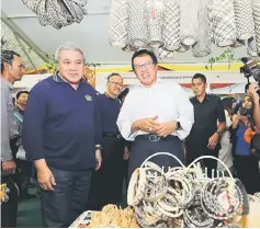  ??  ?? Abang Johari and Awang Tengah (left) admire some of the traditiona­l handicraft­s for sale at the exhibition put up in conjunctio­n with HoB Sarawak NTFP Carnival.