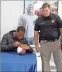  ?? Kevin Myrick ?? Nick Chubb took time out to sign a football for Sheriff Johnny Moats, (out of frame) handed over by Chief Deputy Jonathan Blackmon during the grand opening celebratio­n at Peach State Ford.