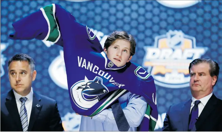  ?? — AP FILES ?? Jared McCann pulls on a Canucks jersey after being drafted 24th overall in 2014. If all goes well, he’ll play for Vancouver and Canada’s world junior team this winter.