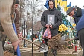  ?? AP PHOTO /ANDREW KRAVCHENKO ?? Cemetery workers bury the coffin of Ukrainian soldier Danylo Lysenko, 22, during his funeral Saturday in Boyarka, near Kyiv, Ukraine.