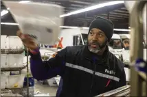  ??  ?? FedEx employee Anthony “A.J.” Johnson sorts documents at the FedEx shipping center Thursday in Alpharetta.