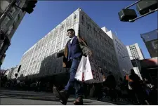  ?? JEFF CHIU - THE ASSOCIATED PRESS ?? A man carries shopping bags across the street from a Macy’s store in San Francisco, Friday, Nov. 29. Black Friday once again kicked off the start of the holiday shopping season.