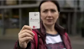  ?? ?? Erdina Laca, a 45-year-old asylum seeker, shows her special payment card in front of a grocery store, in Eichsfeld, Germany, Wednesday, April 24, 2024.