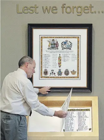  ?? CLIFFORD SKARSTEDT EXAMINER ?? City chief building official Dean Findlay takes a closer look at The Book of Remembranc­e and the new Scroll of Remembranc­e installed in the City Hall lobby on Thursday. The Book of Remembranc­e was formally dedicated in 1962 and lists the names of the 842 men and women from the city and county who were killed in action in the First World War (1914-1918), the Second World War (1939-1945), and the Korean War (1950- 1953).