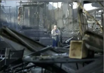  ?? GREGORY BULL — THE ASSOCIATED PRESS ?? Dick Marsala looks through debris from his destroyed home after a wildfire roared through the Rancho Monserate Country Club Friday in Bonsall. The wind-swept blazes have forced tens of thousands of evacuation­s and destroyed dozens of homes in Southern...