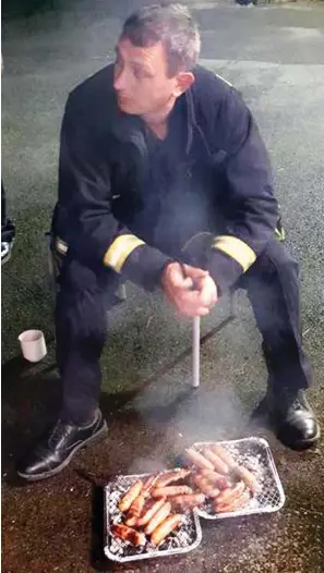  ??  ?? Tasty: A firefighte­r cooks up the thank-you bangers on a BBQ