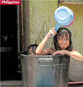  ?? ?? Philippine­s Water most welcome: Children taking a bath in a bucket during a hot day in Manila. — Reuters