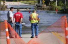  ?? BRE MCGEE — THE FREE PRESS VIA AP ?? Mike Baer, left, Brad O’Donnell and Todd Huxford stand near the edge of the flooded Le Sueur River across Park Street North Saturday in St. Clair, Minn.