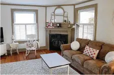  ?? ?? Tucked into one corner of the living room is a gas fireplace with painted wood ornate mantel. The wood accents surround a kidney-shaped triple mirror. The fireplace is angled within the corner so that it can be enjoyed from the entire living room and the adjoining dining room.