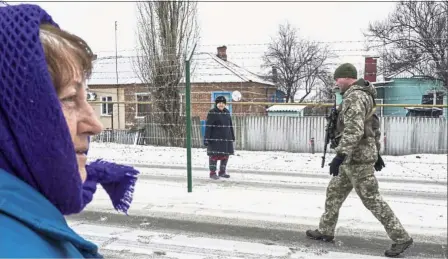  ?? — AP ?? So close yet so far: Boldyreva (left) trying to speak to Yakovleva, standing behind barbed wire on the Russian side of the border as a Ukrainian guard patrols an area in Milove town.