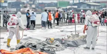  ?? AFP ?? Health workers spray disinfecta­nt over body bags containing human remains recovered from the crash site of Sriwijaya Air flight SJ182 at the port in Jakarta on Sunday, a day after the airline's Boeing 737-500 aircraft plunged into the Java Sea minutes after takeoff.