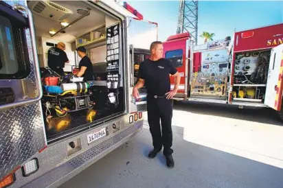  ?? NELVIN C. CEPEDA U-T PHOTOS ?? At the fire station in Borrego Springs recently, engineer paramedic Trey Nelson waits outside the ambulance as firefighte­r paramedics Robert Amaya (left) and Fernando Ayala check gear and supplies in the rig at the start of their shift.