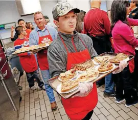  ?? [PHOTO BY NATE BILLINGS, THE OKLAHOMAN ?? The Salvation Army is known for its outreach programs that aid the homeless and impoverish­ed like the 2017 Thanksgivi­ng meal in Oklahoma City, where volunteer Carter Morey distribute­d slices of pie. While those programs treat the symptoms of poverty,...