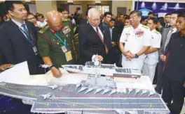  ??  ?? Najib is flanked by Armed Forces chief Jen Tan Sri Raja Mohamed Affandi Raja Mohamed (left) and Navy chief Adm Tan Sri Ahmad Kamarulzam­an Ahmad Badaruddin as he views a model of an aircraft carrier at DSA 2018 in Kuala Lumpur yesterday.