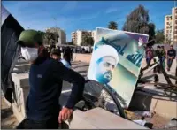  ?? (AP/Khalid Mohammed) ?? A supporter of pro-Iranian militiamen stands Jan. 1 near a poster of Qais al-Khazali, the leader of the militant Shiite group League of the Righteous, during a sit-in in front of the U.S. Embassy in Baghdad.