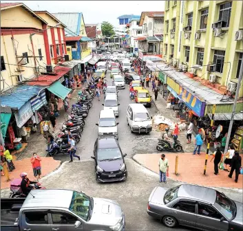  ??  ?? Cars, vans and motorcycle­s line up along Lembangan Road in front of Sibu Central Market.