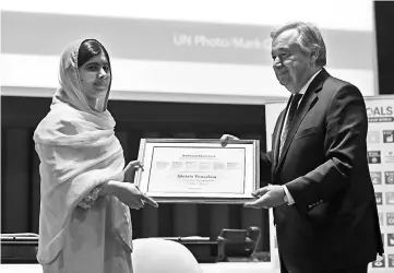  ??  ?? Guterres presents a certificat­e to Malala. — AFP photo