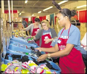  ??  ?? Volunteer Avia Meadows (right) helps sort bins of clothing at Santa’s Village. The Empty Stocking Fund’s toy and gift warehouse and distributi­on center provided gifts this year to nearly 50,000 children in need.