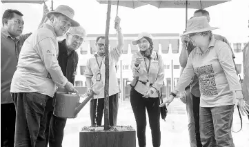  ??  ?? Jeanne looks on as Abdullah waters a tree during the Our Forest Trees Planting @ Parliament programme. Also seen is Abdul Halim (second left) and Parliament Secretary Datuk Roosme Hamzah (second right). — Bernama photo