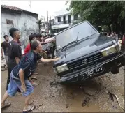  ?? ACHMAD IBRAHIM — THE ASSOCIATED PRESS ?? Residents move the wreckage of cars that were swept away by floods in Bekasi, West Java, Indonesia, on Friday,