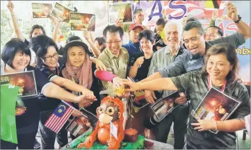  ??  ?? Abang Arabi (second right) and Chong (front  fth right) leads some of the adopters to cut the birthday cake for baby orangutan Mas.