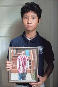  ?? MICHELLE KANAAR/THE TRACE ?? Htee Moo, 13, holds a portrait of his father, Jay Ro, at the family's new home on the south side of Milwaukee on Sept. 6.