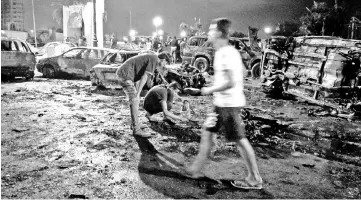  ??  ?? People look at the remnants of vehicles at the scene of a car bombing in Benghazi. — Reuters photo