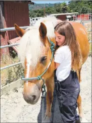  ??  ?? Eight-year-old Evelyn Williams cuddles with Gus, which is apparently one of her favorite things to do at Bear Creek Stables. “I really like petting the horses and riding them on the trail,” she said.