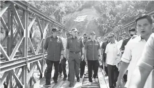  ?? — Gambar Bernama ?? TINJAU: Najib meniti jambatan besi ketika meninjau pembinaan Jalan Telipok-Pekan Kiulu-PukakPahu-Lokos-Toboh-Randagong di Kampung Pukak di Kiulu semalam.