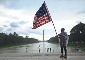  ?? ANDREW CABALLERO-REYNOLDS/AFP VIA GETTY IMAGES ?? A demonstrat­or waves an American flag with the words “Not Free” painted on it in front of the Washington Monument during a Juneteenth march last June.