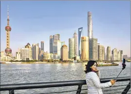  ??  ?? A visitor takes a selfie in the backdrop of Shanghai’s skyline.