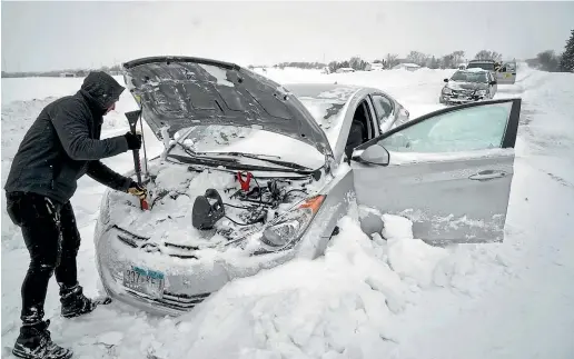  ?? AP ?? Isaac Baker attempts to help a friend with his vehicle which had stalled near Owantonna, Minnesota, the day before. Dangerous cold once again gripped the Upper Midwest yesterday, following a deadly blizzard that caused multiple pileups, paralysed highways, and stranded motorists.