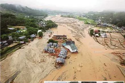  ?? AGENCY PIX ?? An aerial view of flooded Asakura City in Fukuoka prefecture yesterday. (Inset) Firefighte­rs evacuating residents from Asakura City.