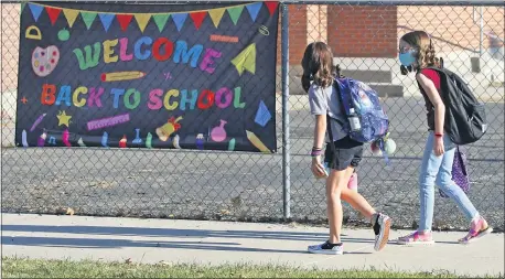  ?? RICK BOWMER — THE ASSOCIATED PRESS FILE ?? Cimmie Hunter, left, and Cadence Ludlow, both 6th graders, arrive at Liberty Elementary School during the first day of class in Murray, Utah, earlier this week.