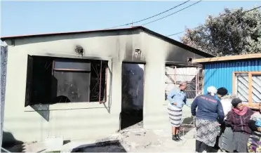  ?? | SISONKE MLAMLA ?? COMMUNITY members survey the home where a mother and her children burned to death in Khayelitsh­a yesterday.