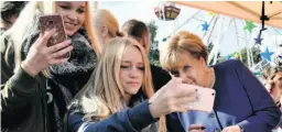 ?? JOHN MACDOUGALL / AFP / GETTY IMAGES ?? German Chancellor Angela Merkel poses for a selfie at a town fair in Stralsund this month. After 12 years in power, Merkel is poised to claim a fourth four-year term in Sunday’s vote.