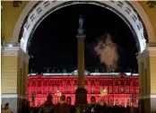  ?? — AP ?? People walk past the Winter Palace, the State Hermitage Museum museum, illuminate­d in red for the upcoming 100th anniversar­y of the Bolshevik’s revolution in St.Petersburg, Russia, on Wednesday.