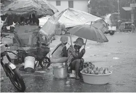  ?? [DIEU NALIO CHERY/ THE ASSOCIATED PRESS] ?? Street vendors protect themselves against the rain from Tropical Storm Laura, Sunday in Port-au-Prince, Haiti.