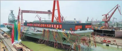  ?? LI GANG / XINHUA ?? China’s third aircraft carrier, the CNS Fujian, is towed out of its dry dock at China State Shipbuildi­ng Corp’s Jiangnan Shipyard Group in Shanghai at a launch ceremony on June 17. The carrier, which has much greater combat capabiliti­es than its two predecesso­rs, will undergo mooring and sea trials to comprehens­ively test its overall capabiliti­es and specific equipment.