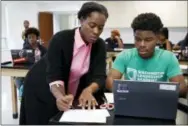  ?? JACQUELYN MARTIN — THE ASSOCIATED PRESS ?? Britney Wray, a math teacher at Washington Leadership Academy, helps sophomore Kevin Baker, 15, with a math problem during class in Washington, Wednesday. Students took diagnostic tests using special software. As they solved math problems on their...