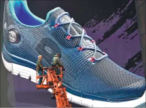 ?? TIMOTHY A. CLARY / AFP ?? Two workers install a billboard for Reebok in Manhattan, New York.