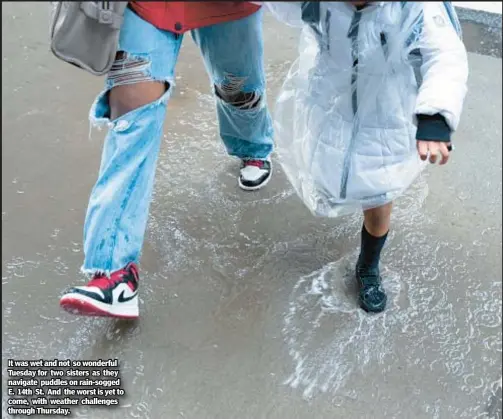  ?? ?? It was wet and not so wonderful Tuesday for two sisters as they navigate puddles on rain-sogged E. 14th St. And the worst is yet to come, with weather challenges through Thursday.