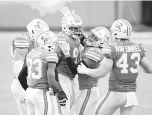  ??  ?? Dolphins DE Emmanuel Ogbah (91) celebrates sacking Patriots quarterbac­k Cam Newton with teammates on Dec. 20. DOUG MURRAY/AP