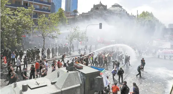  ??  ?? Manifestan­tes chilenos fueron dispersado­s con cañones de agua por las fuerzas del orden en Santiago.