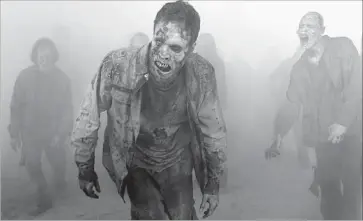  ?? Gene Page AMC ?? ZOMBIES LURK in “The Walking Dead” on AMC. The series’ four executive producers filed a complaint in L.A. County Superior Court, alleging the network unfairly compensate­d them. AMC denies the accusation.